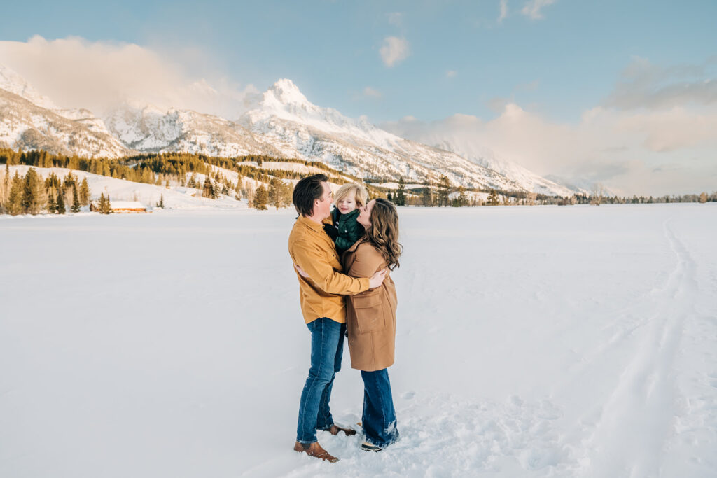 outdoor winter family photoshoot in snowy Jackson Hole landscape, family photo outfits for winter, earth-toned casual outfit inspiration