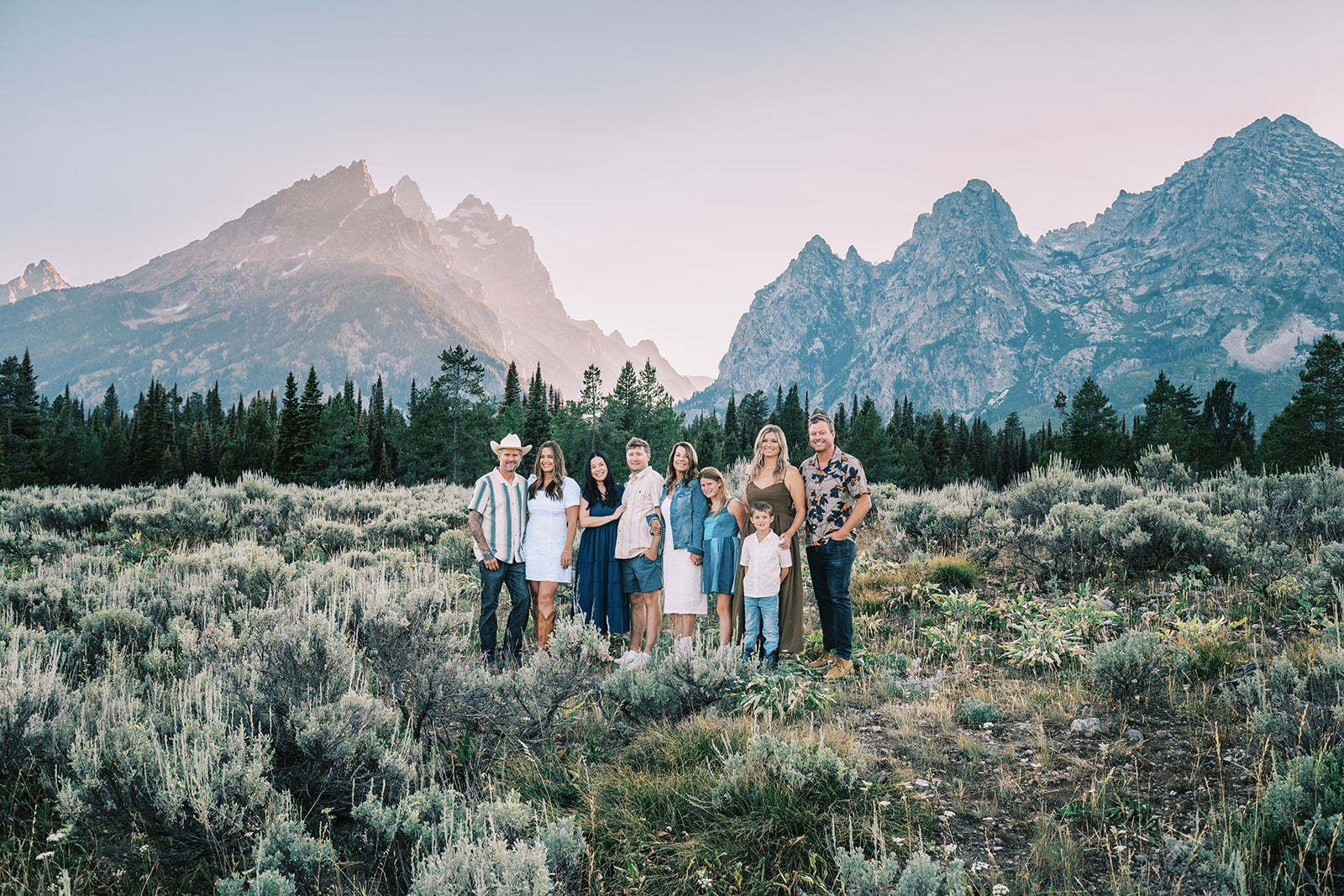 Family posing together in a field with the Grand Tetons in the background