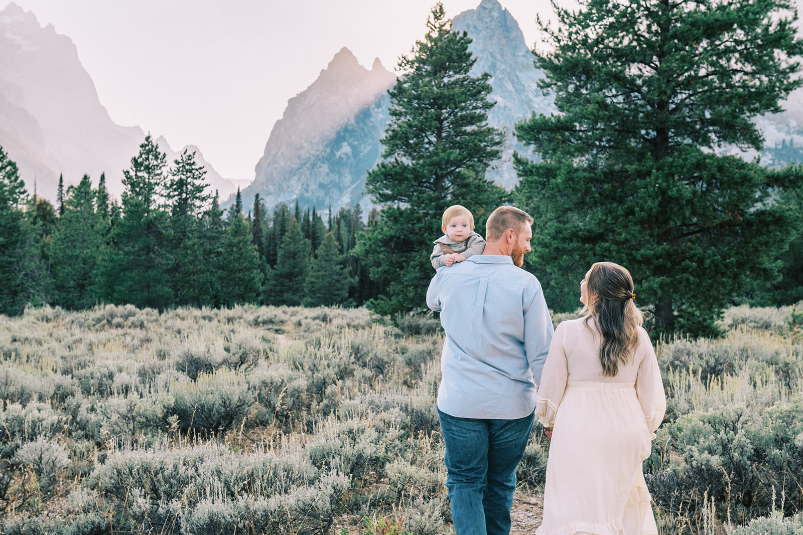surprise proposal session GTNP, mom and dad walking in the Grand Tetons with baby over the dad's shoulder