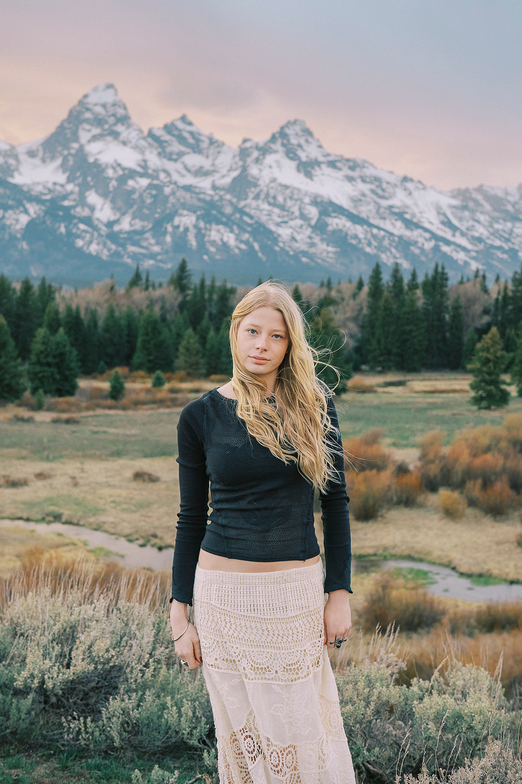 A high school senior in a black shirt and lace skirt stands in a valley on a windy day after finding graduation party venues in Jackson, WY