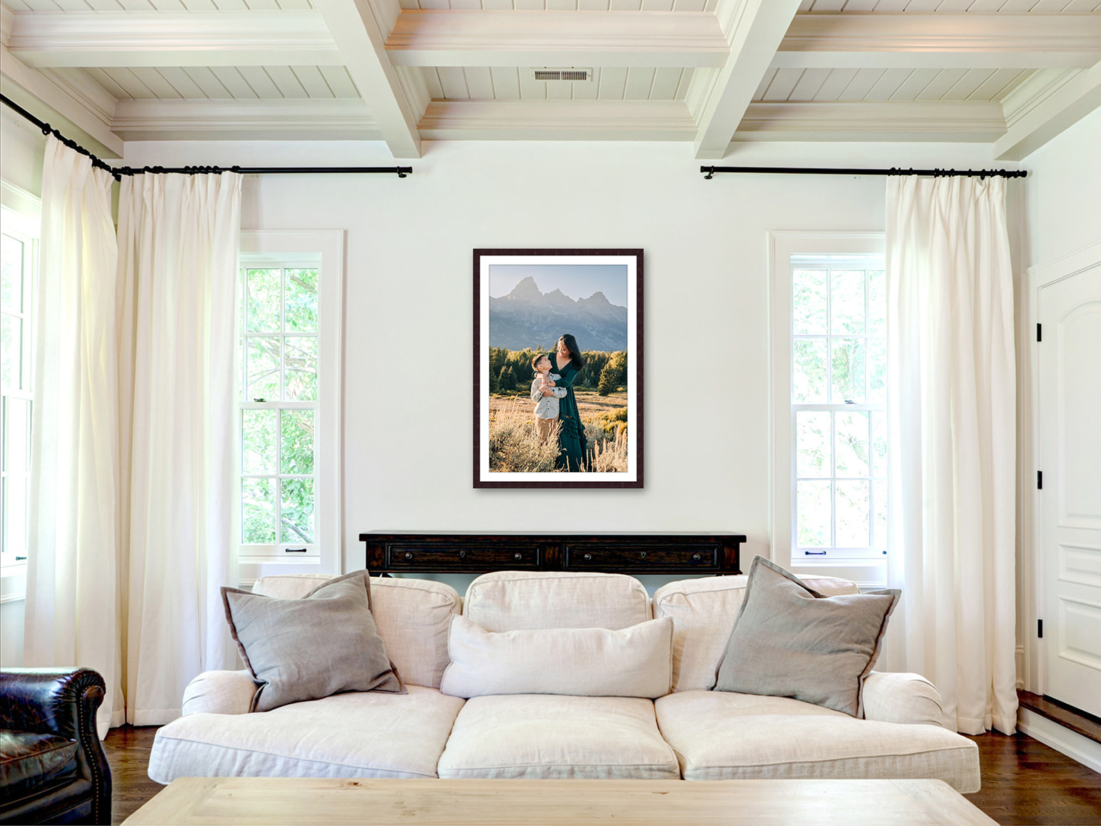 A portrait of a mom hugging her son in a meadow hangs on a wall over a couch as an example of how to display your family portraits