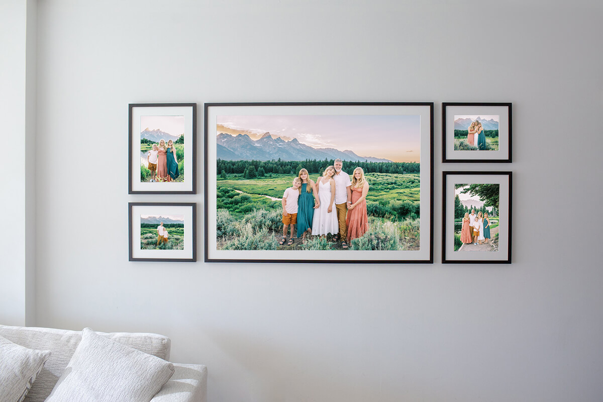 An araingment of fine art framed photos of a fmaily of five hangs on a wall after learning how to display your family portraits