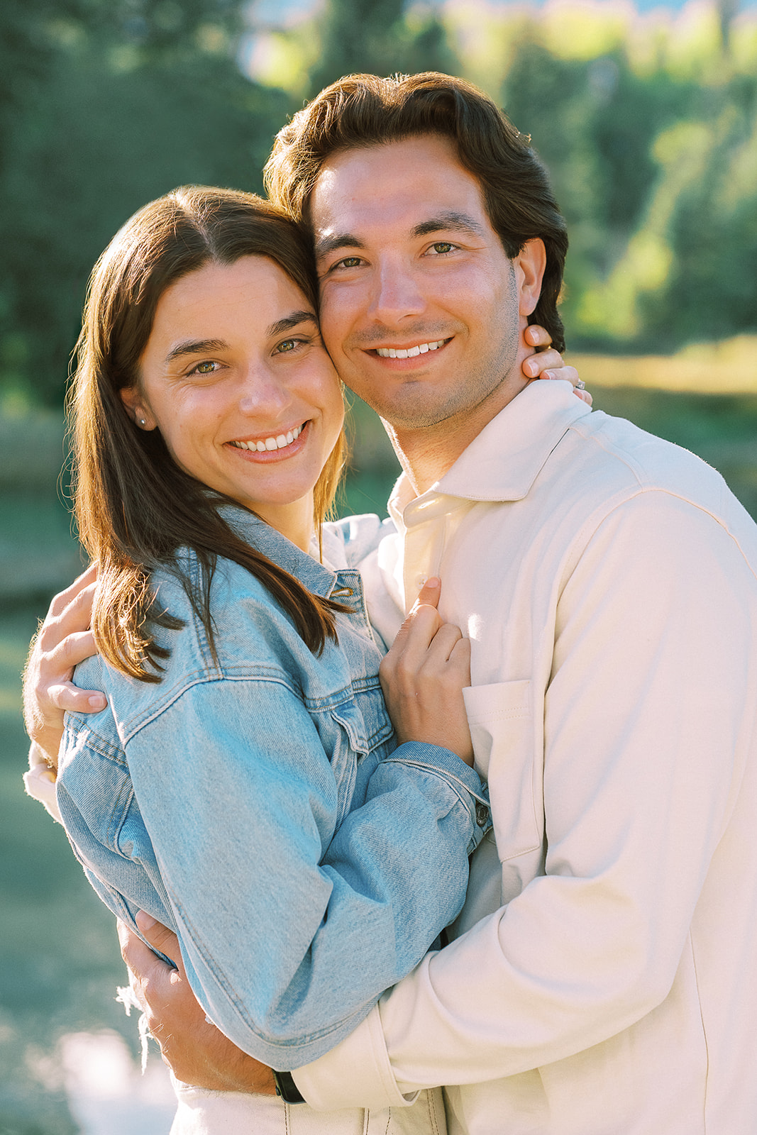 A happy couple stand cheek to cheek in an embrace while smiling