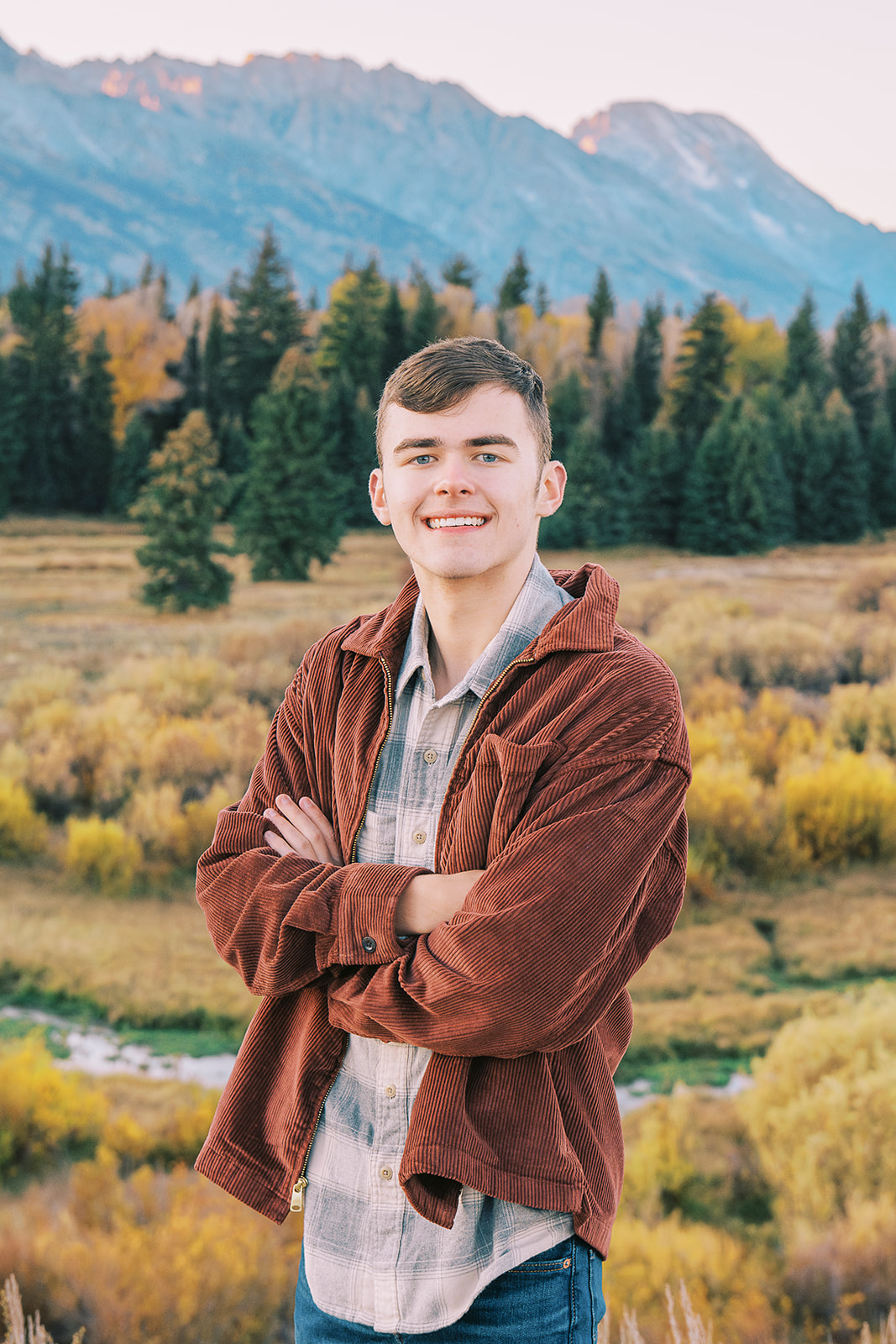 A high school senior in a plaid shirt and brown jacket in fall after finding great tuxedo rental in Jackson, WY